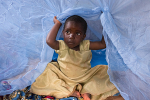 A child sits under a mosquito net in Tanzania
