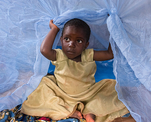 A child sits under a mosquito net in Tanzania