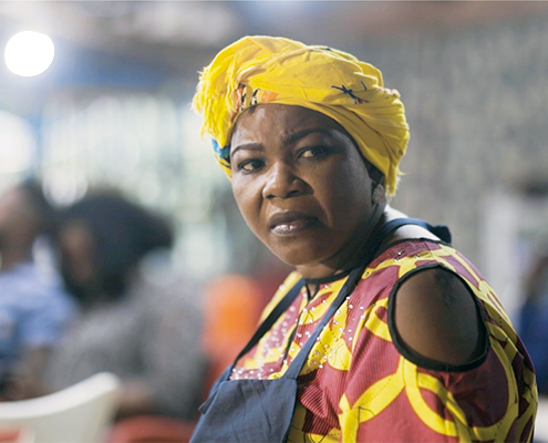 A woman, Mama Put, in her restaurant, with a concerned look on her face.