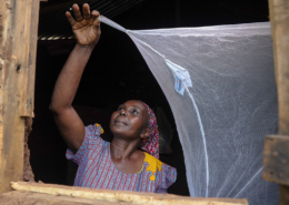 A woman installing a mosquito net in her home in Kenya