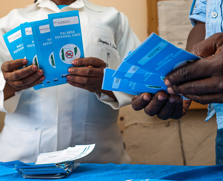 Two health care workers hold malaria referral cards in Nigeria