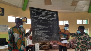 Two men holding up a chalk board and one man pointing to data on the board.