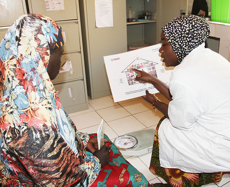 A health care provider discusses a nutrition brochure with a woman during a user-testing session in Niger