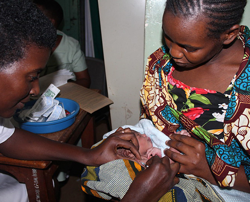 A health care provider vaccinates a newborn in its mother's arms