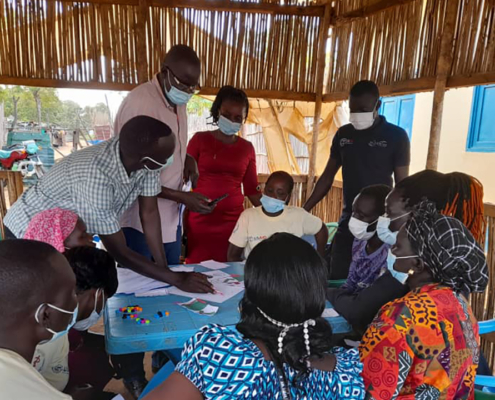 People gather around a table during the design and test phase in South Sudan