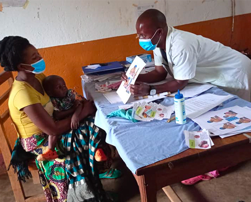 Healthcare worker showing a Breakthrough ACTION tool on complementary feeding of a child who is sick to a mother.