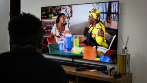 A Nigerian man watching a malaria spot featuring the character Mama Put.