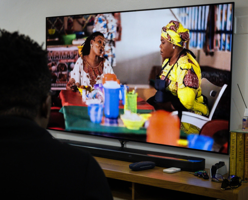 A Nigerian man watching a malaria spot featuring the character Mama Put.