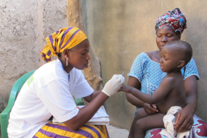 Community health worker administering malaria rapid diagnostic test (RDT) to a young child in Mali.