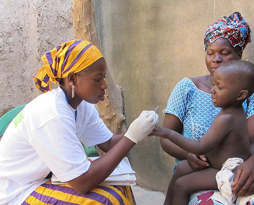 Community health worker administering malaria rapid diagnostic test (RDT) to a young child in Mali.